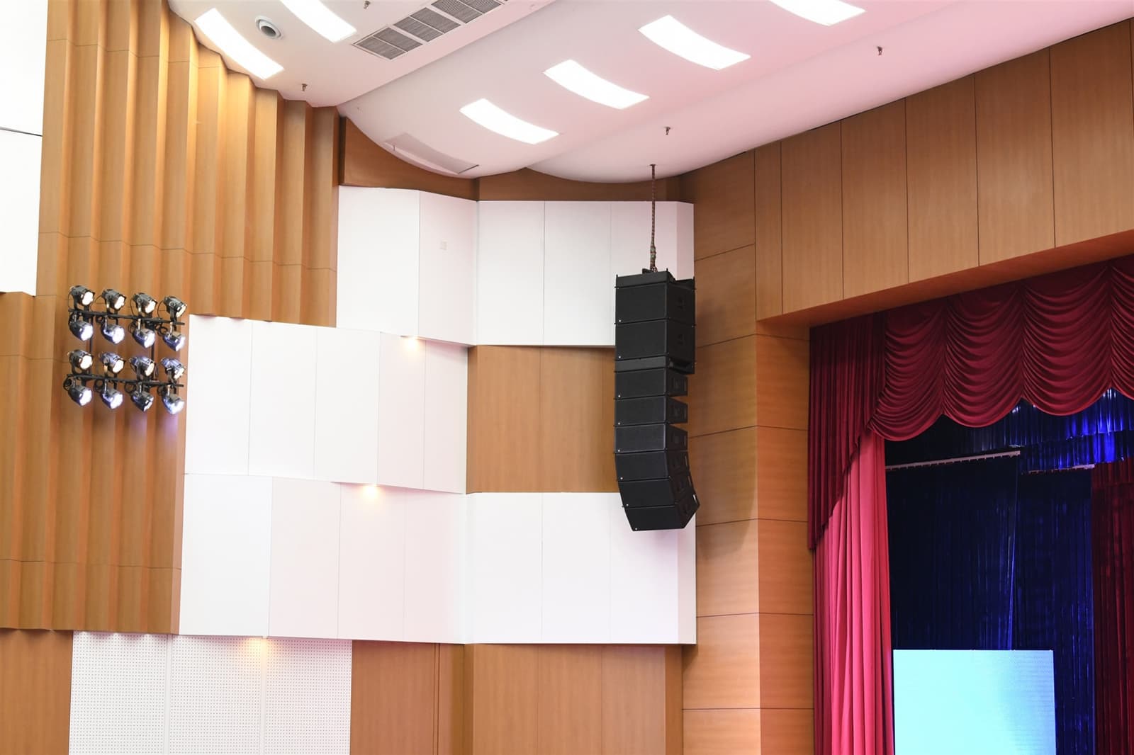 Cụm loa line-array EAW treo bên cạnh các tấm ốp tán âm, định hướng âm vào mặt phẳng khán giả.